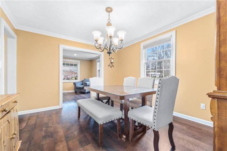 Alternate angle showcasing the seamless flow from dining to living room, enhanced by bright windows and classic trim details.
