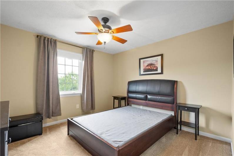 Bedroom 3 features neutral walls and carpet, a ceiling paddle fan, and a spacious closet—offering comfort and practicality.