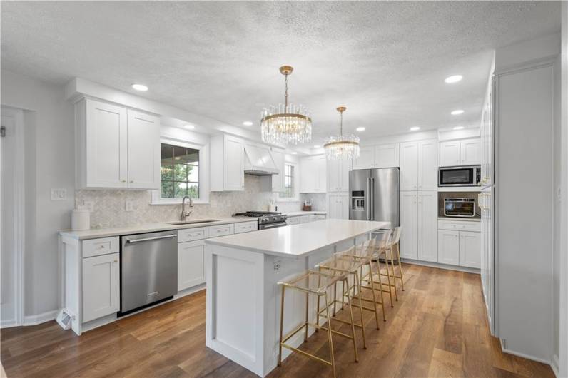 The kitchen is bright and inviting, featuring a mix of recessed lights and stylish pendant fixtures that create a warm, well-lit space perfect for cooking and gathering.