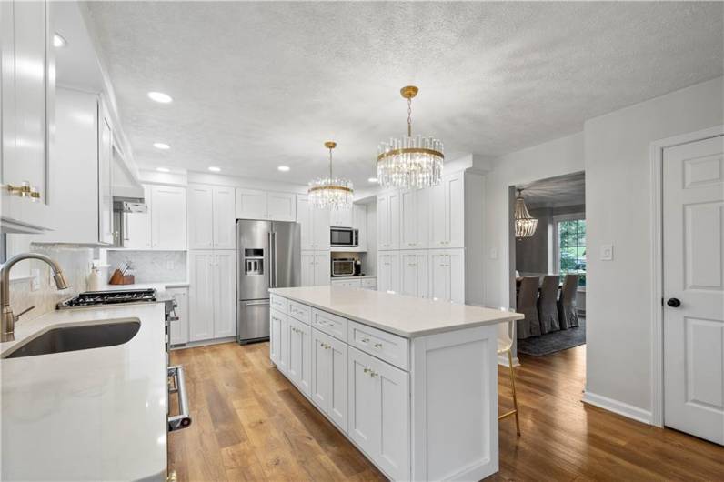 Beautiful white cabinets paired with quartz countertops and a stylish tile backsplash create a fresh, modern look. Gorgeous new flooring completes the space, making this kitchen truly stand out.