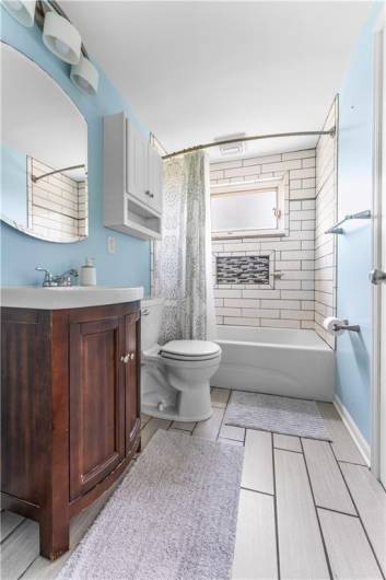 The first floor bath features ceramic tile floor, vanity and tub.