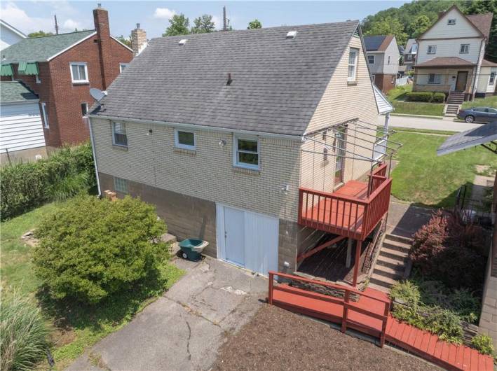Stairs and walkway lead to back yard, driveway and concrete patio.