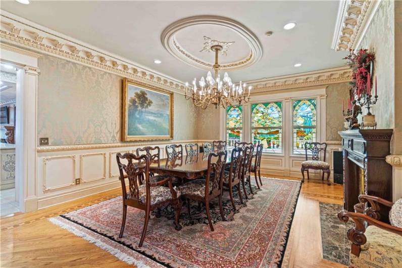 formal dining room with gas fireplace and stained glass windows...intricate mouldings and fabric wall coverings